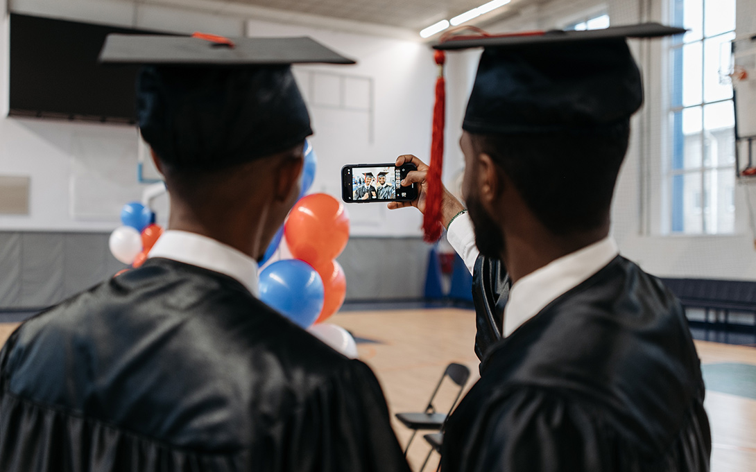 Photo of two students in their cap and gown taking a selfie